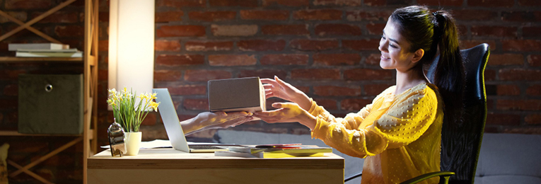 An illustrative image showing a woman receiving a gift box from hands emerging out of her laptop.